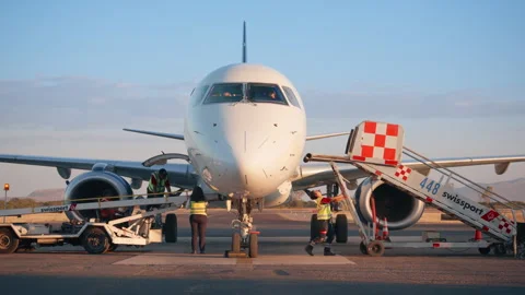 Ground crew workers preparing white passenger jet for departure at sunset. Stock Footage 337906547