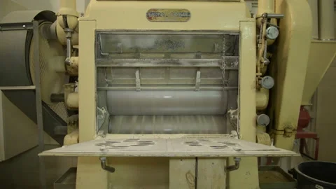 Ground flour is pouring from a mill that grinds whole grain wheat at a mill Stock Footage 173472220
