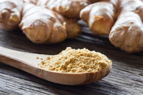 Ground ginger with fresh ginger root in the background Stock Photos