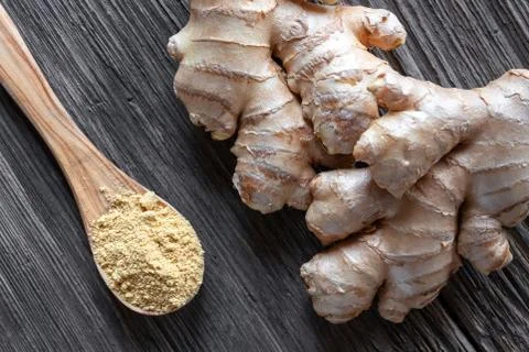 Ground ginger on a spoon with and ginger root on a table Stock Photos