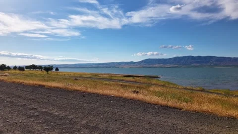 Ground-Level Push Through Golden Grass Toward Tranquil Blue Lake Stock-Footage 339764942