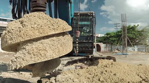 Ground Level Static Shot of Piling Rig Discharging Soil and Drilling Stock Footage 342057538