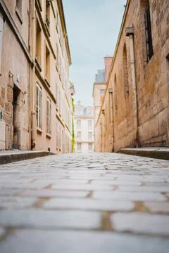 Ground Level View of a Cobblestone Allay with Old and Weathered Building Wall Stock Photos