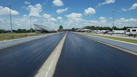 Ground level view down an empty drag strip toward distant grandstands under a Stock Footage 346147258