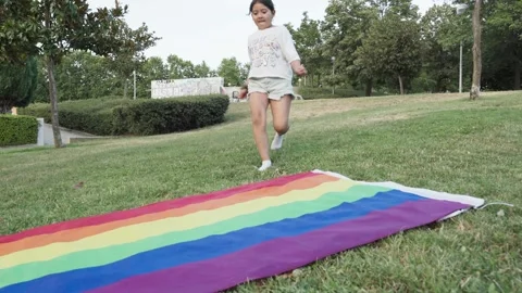 Ground Level View Of Girl Running Toward LGBTQ Flag Lying On Grass.MOV 스톡 동영상 251496841