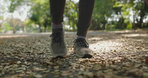 Ground level view of gray knit running shoes on a park path Vídeo Stock 331232589