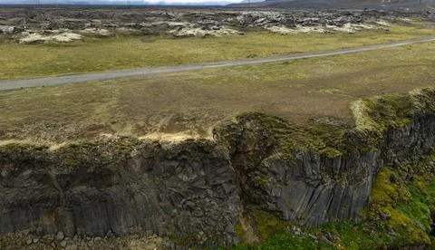 Ground-level view of hexagonal columnar basalt cliffs with thick moss and lic Stock-Fotos