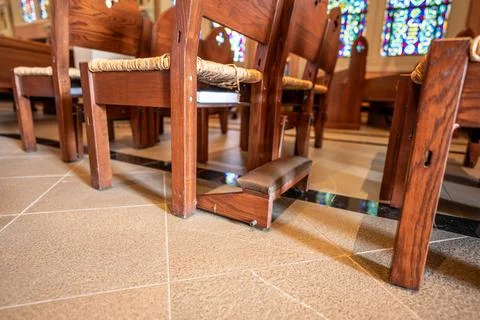 Ground level view of kneeling bench rows in a church used for praying. Stock Photos