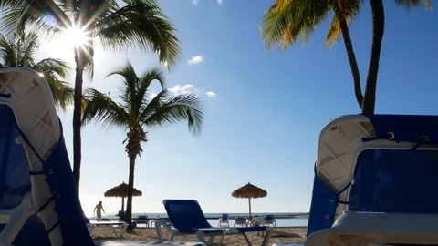 Ground level view of a paradise beach between sun chairs and a beautiful sunset Stock-Footage 121479322