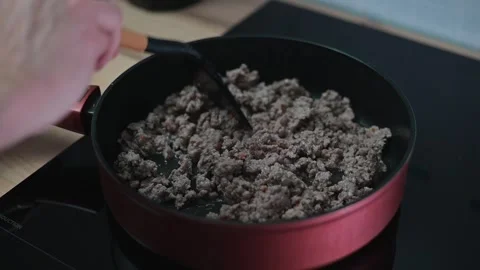 Ground meat is being cooked in a frying pan on a stovetop. A spatula is used to 스톡 동영상 337111938