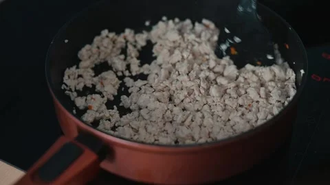 Ground meat is being cooked in a pan over medium heat, with a spatula stirring Stock Footage 339094463