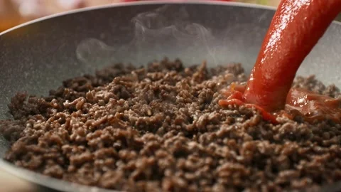 Ground Meat Frying in a Pan with a Stream of Red Tomato Sauce Pouring over it Stock Footage 278831006