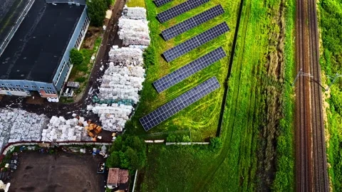 Ground mounted solar panel array next to a recycling plant. 库存影片 344522425