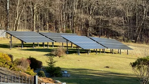 A ground mounted solar panel array stands in a grassy rural field, showcasing a Vídeo Stock 345822829