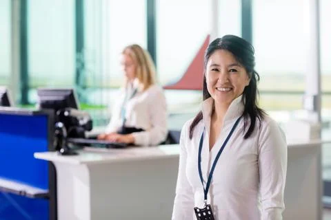 Ground Staff Smiling While Colleague Working At Airport Receptio Stock Photos