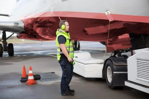 Ground Worker Standing By Airplane With Communication Cable On R 스톡 사진