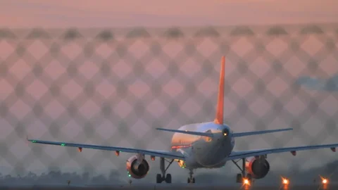 Grounded airplane at sunset, view through the barrier net Vídeo Stock 112561444