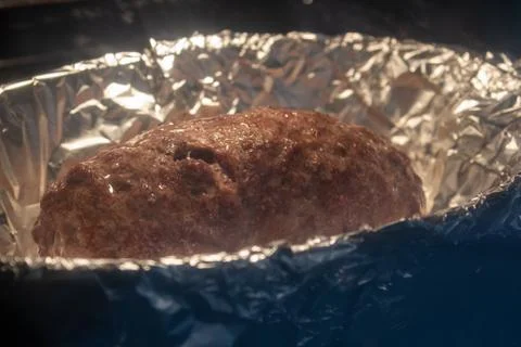 Grounded beef rolled with ham and cheese inside, on a foil tray inside the ov Foto stock