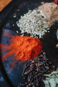 Grounded chili pepper on black rustic surface, surrounded by spices. Stock Photos