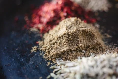 Grounded pepper surrounded by spices over black surface. Stock Photos