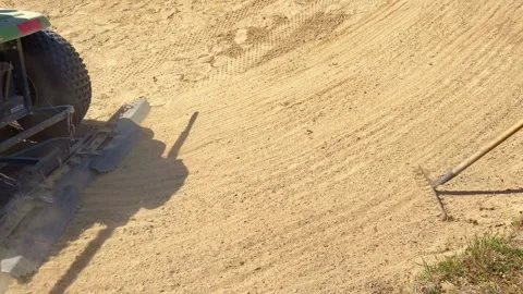 Groundskeeper grooming golf bunker with maintenance vehicle 库存影片 341710507