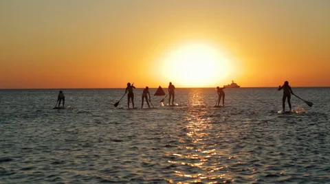 Group of Active Athletic People Engaged in Sup-Surfing on the Sea at Dusk Stock Footage 61868672