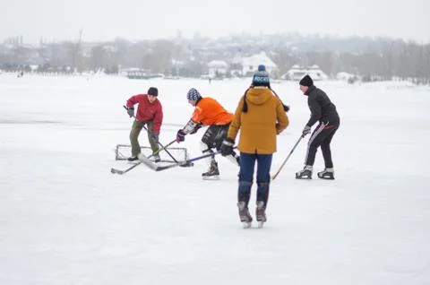 Group of active different age and sex people playing hokey on a frozen river Foto stock