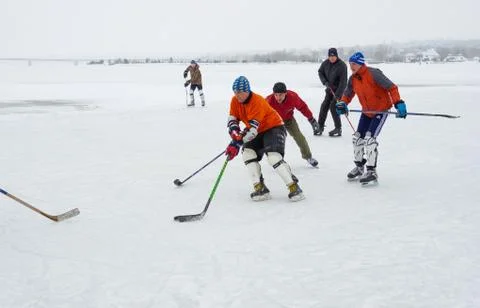 Group of active different aged people playing hokey on a frozen river Dnipro Stock Photos