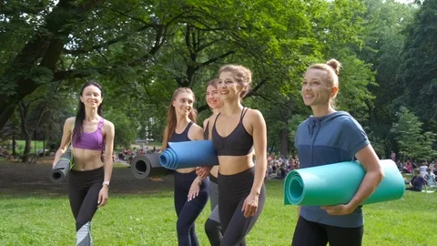 Group of active five smiling female going for workout, holding yoga mats in Stock Footage 111941112