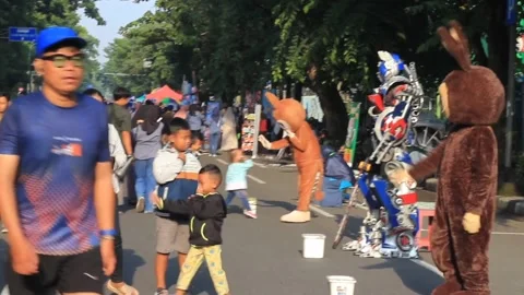 Group of adults and children interact with animal and robot mascots Stock Footage 296133469