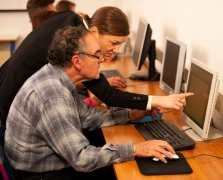 Group of adults learning computer skills. Intergenerational transfer of knowl Stock Photos