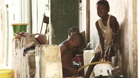 A group of African children bathe under a hose outside in a slum. Stock Footage 212100852