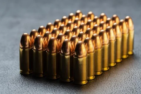 Group of aligned 9 mm bullets isolated on dark background viewed from side Stock Photos