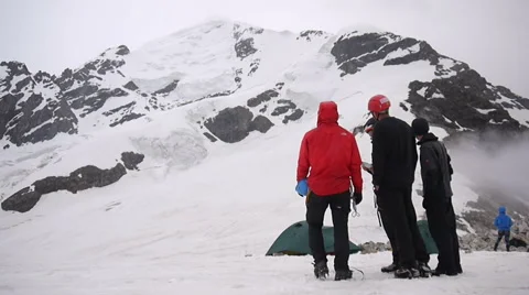 Group of Alpine Climbers looking at the snow covered mountain from the camp Stock Footage 43249176
