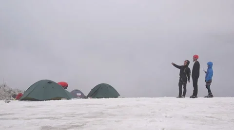 Group of Alpine Climbers standing by their tents in snow Stock Footage 43249178