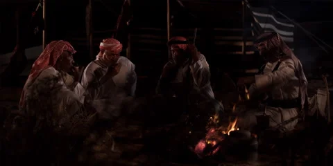 A group of Arabic men sit around a camp fire in a desert at night. Stock Footage 46870488