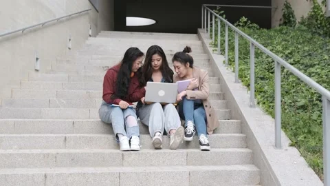 Group of Asian female students using a laptop and studying together while sit Stock Footage 152097999
