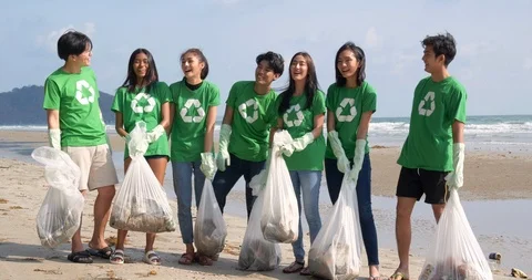 Group of asian people cleaning up the beach with plastic bags full of garbage. Stock Footage