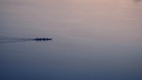 Group of athletes rowing oars in a canoe at sunset Stock Footage 116026710