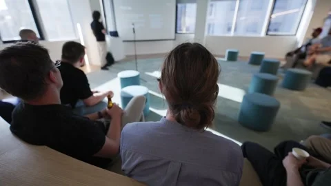 Group of attendees watching a presentation in a modern office space with Stock Footage 335948628