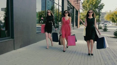 Group of attractive young women walking along shop windows. Slow motion Stock Footage