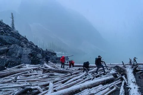 Group of backpacker walking on snowy log wood in blizzard at national park Stock Photos