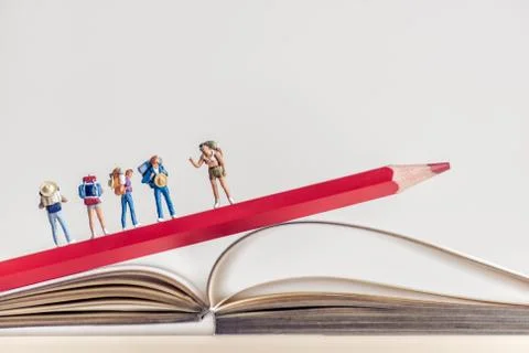 Group of backpackers walking over opened book. Travel concept Stock Photos