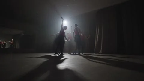 A group of ballerinas spin one after the other in a beam of light. Video stock 245750802