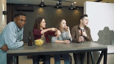 Group of best friends drinking beer and preparing to watch a movie on TV at home Stock Footage 123121507