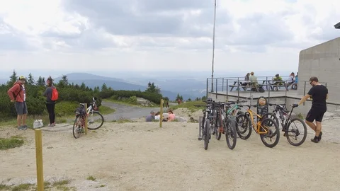 A group of bikes on top of a mountain next to a building, people stand and walk Stock-Footage 122770496