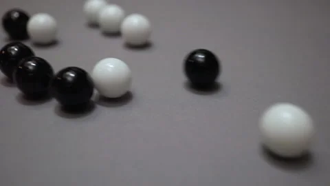 Group of black and white balls rolling across gray surface Stock Footage 147459544