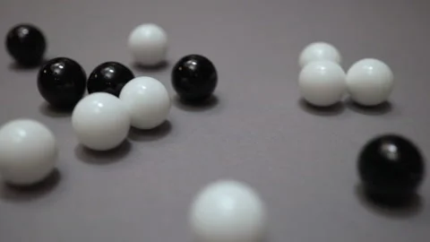 Group of black and white balls rolling across gray surface Stock Footage 147461096
