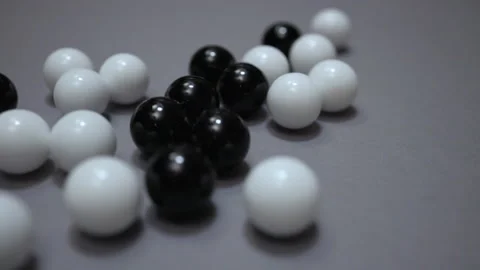 Group of black and white balls rolling across gray surface Stock Footage 147461740