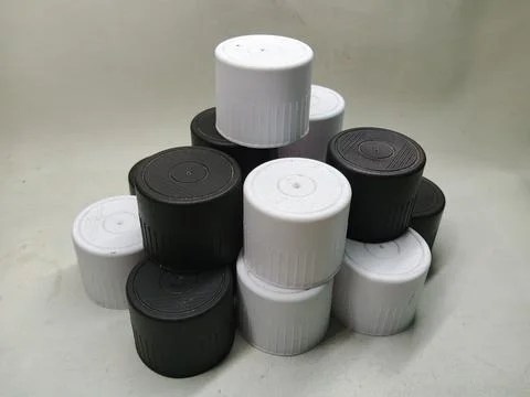 Group of Black and White Plastic Bottle Caps Stacked on White Surface Stock Photos